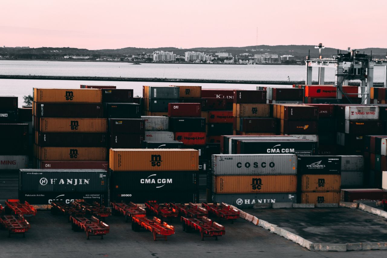 services-03 A bustling container yard at a seaport with shipping containers stacked and ready for transport at twilight.