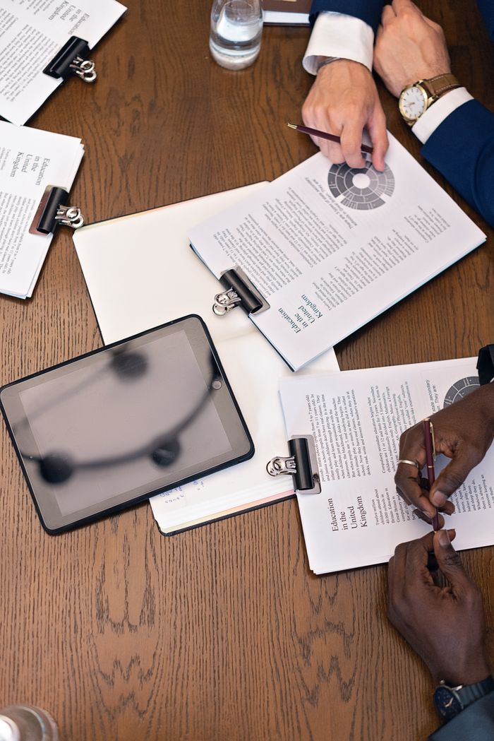 services-04 Top view of a business meeting with hands, tablets, and documents on a table.